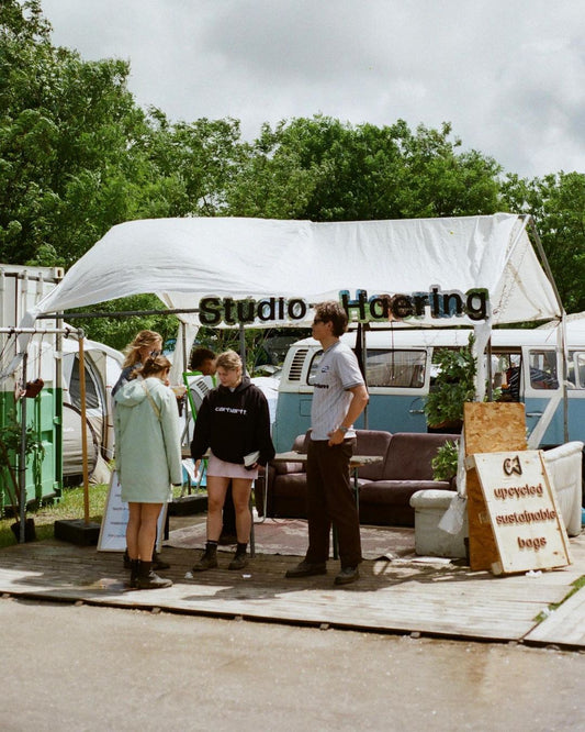 Festival visitors viewing the Studio Haering stand at Wildeburg festival where upcycled festival bags are sold and used tents are collected.