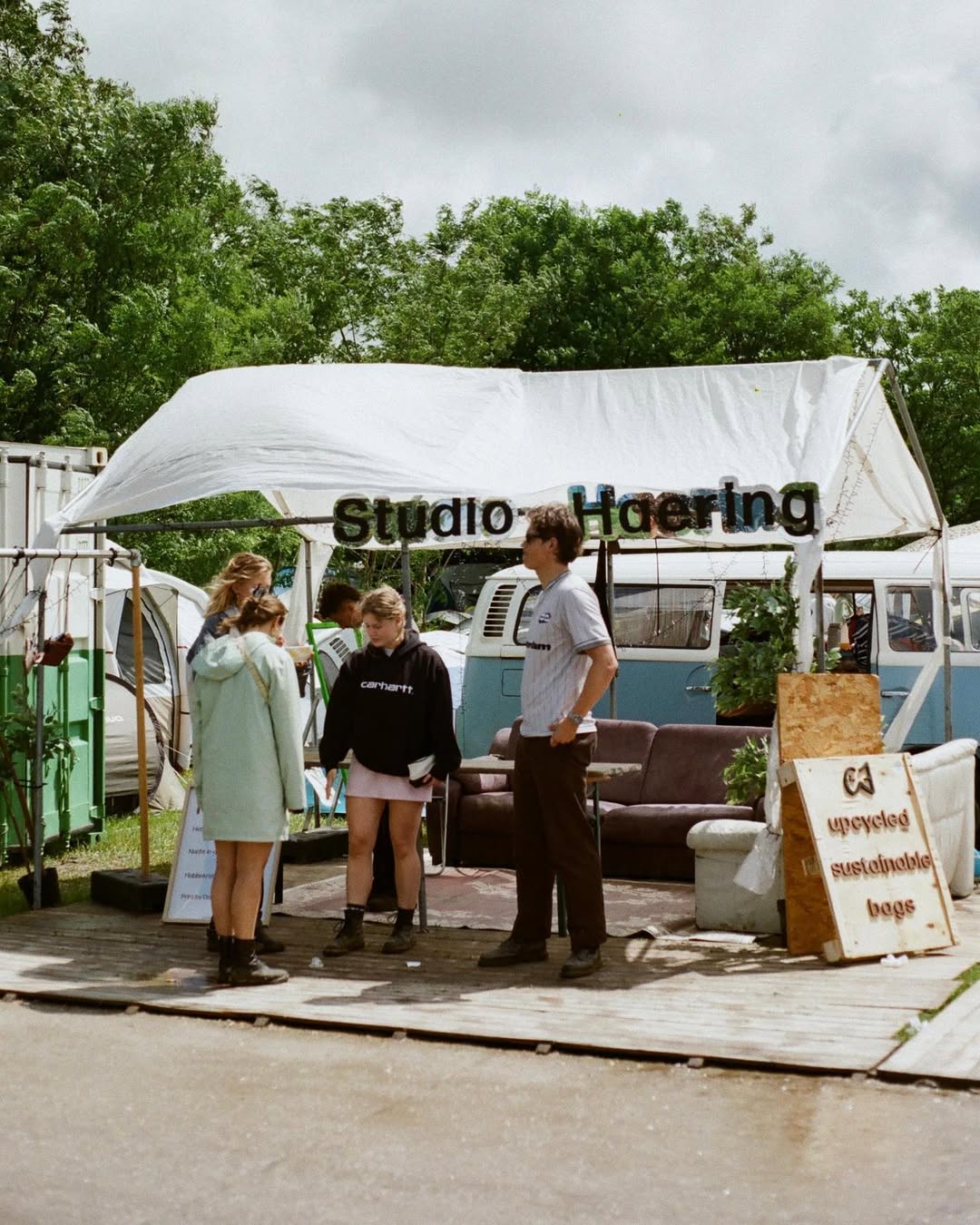 Festival visitors viewing the Studio Haering stand at Wildeburg festival where upcycled festival bags are sold and used tents are collected
