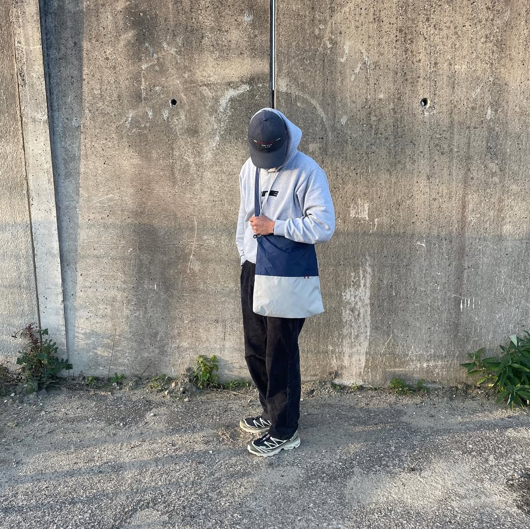 Man in urban streetwear clothing wearing a blue and white Studio Haering sustainable tote bag.