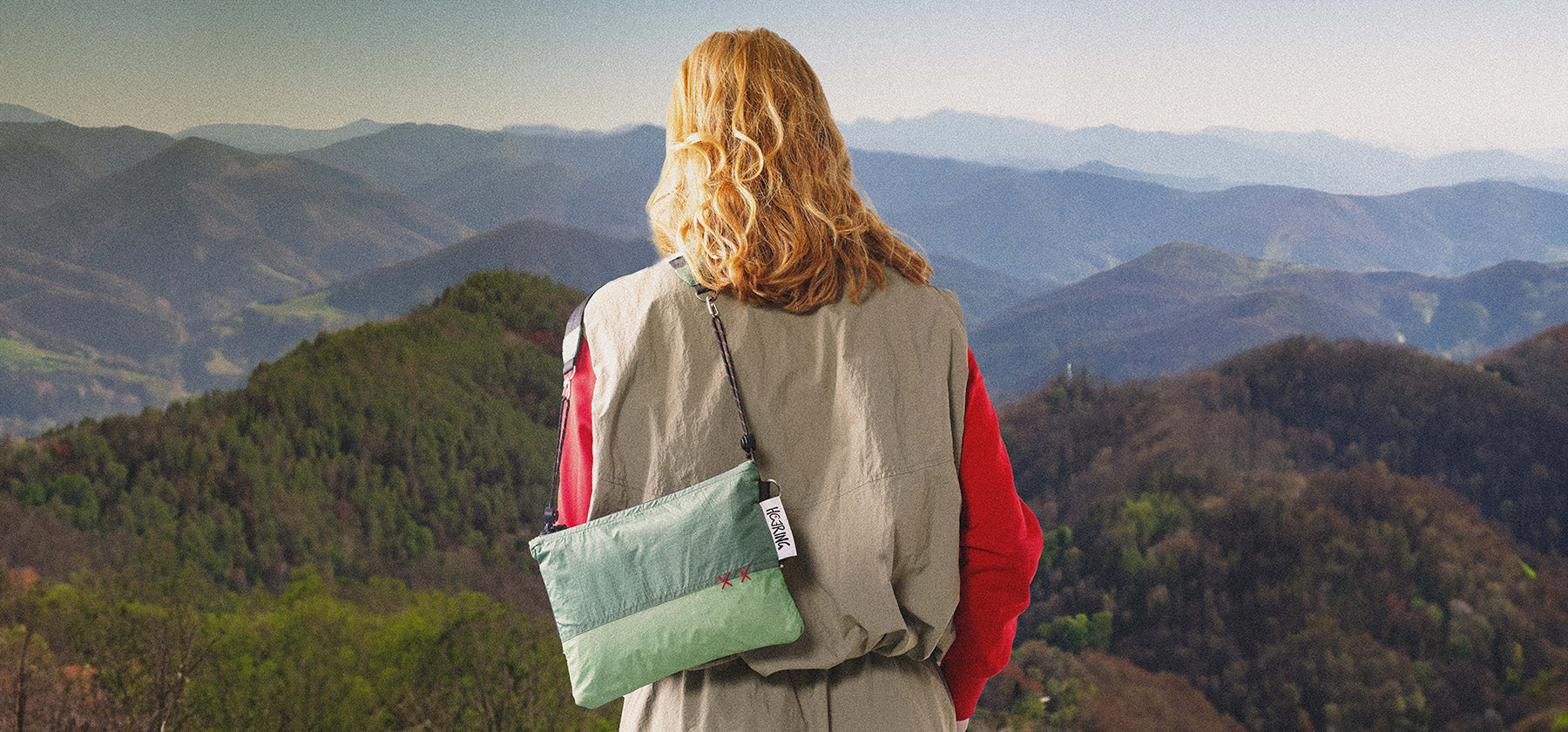Person wearing a green upcycled crossbody Studio Haering bag whilst adventuring outdoors