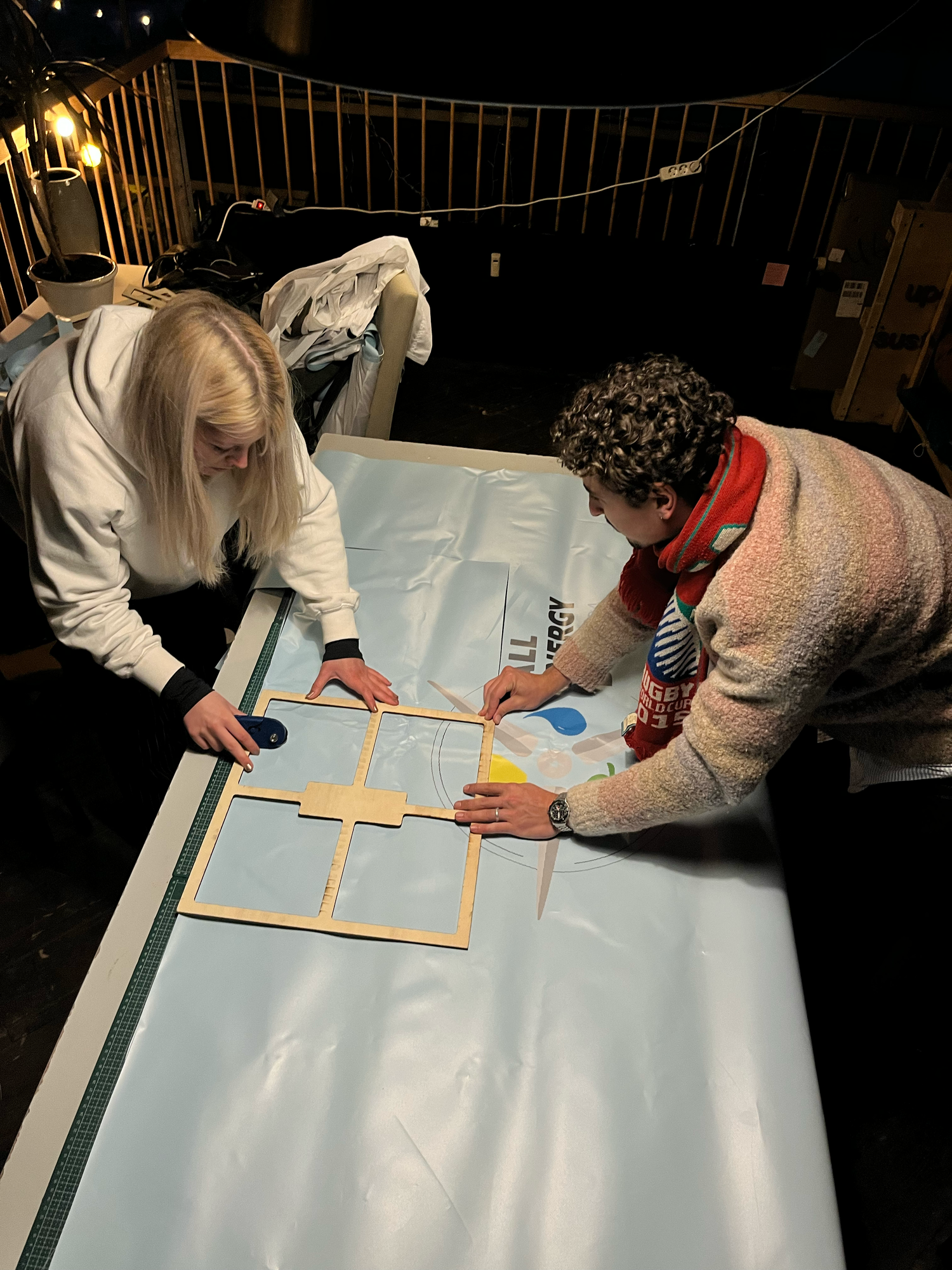 Two designers cutting up an old event banner into patterns during the upcycling phase of Studio Haering's creative process.
